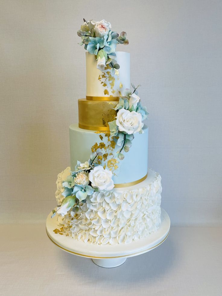 a three tiered cake with white and blue flowers