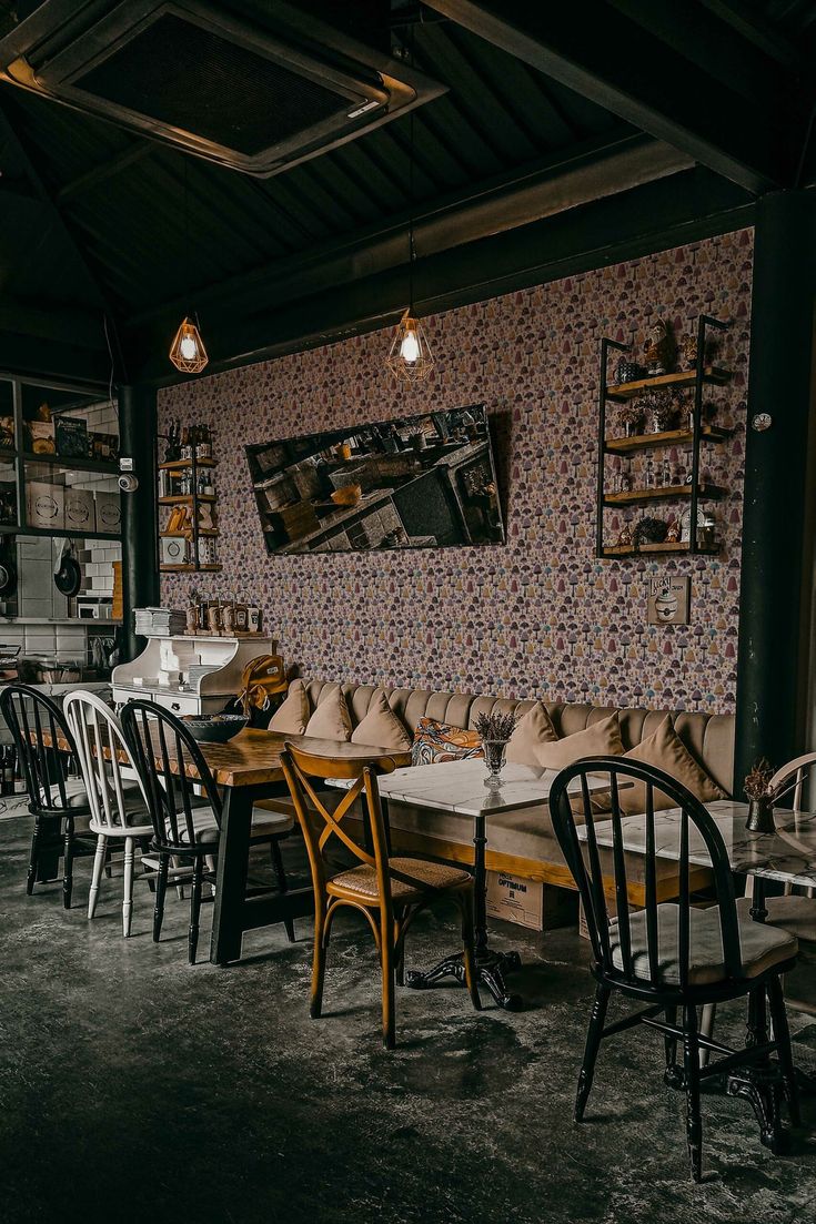 a restaurant with wooden tables and chairs in front of a floral wallpapered wall