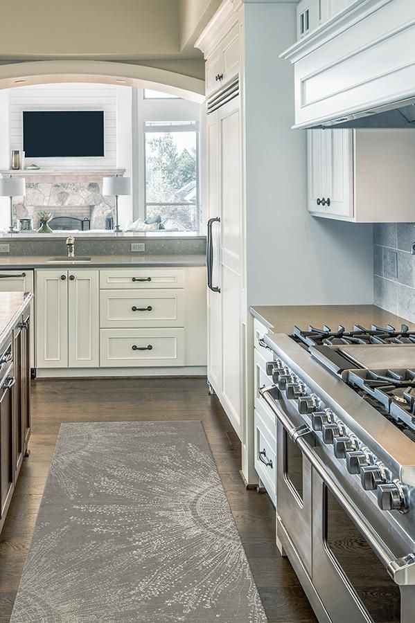 a large kitchen with white cabinets and stainless steel stove top oven next to an area rug