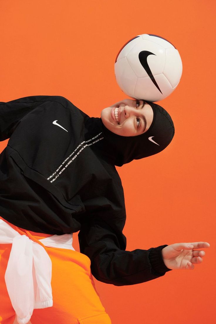 a man in an orange skirt is holding a soccer ball and smiling at the camera