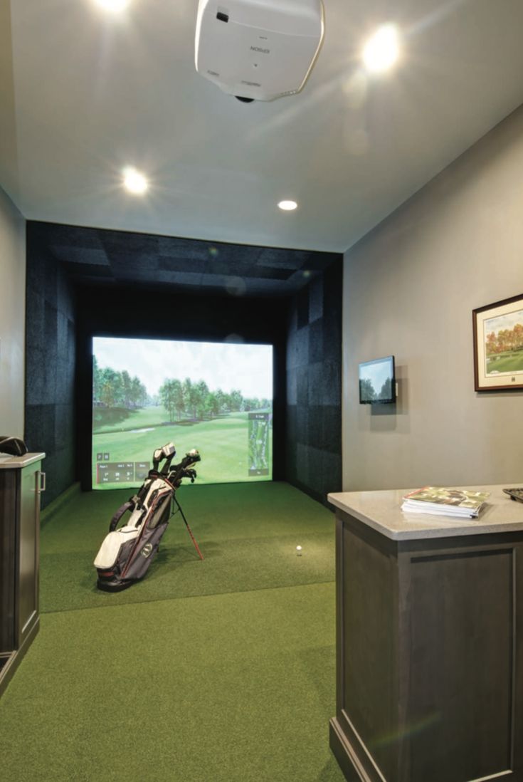 a golf simulator is set up in the middle of a room with green carpeting