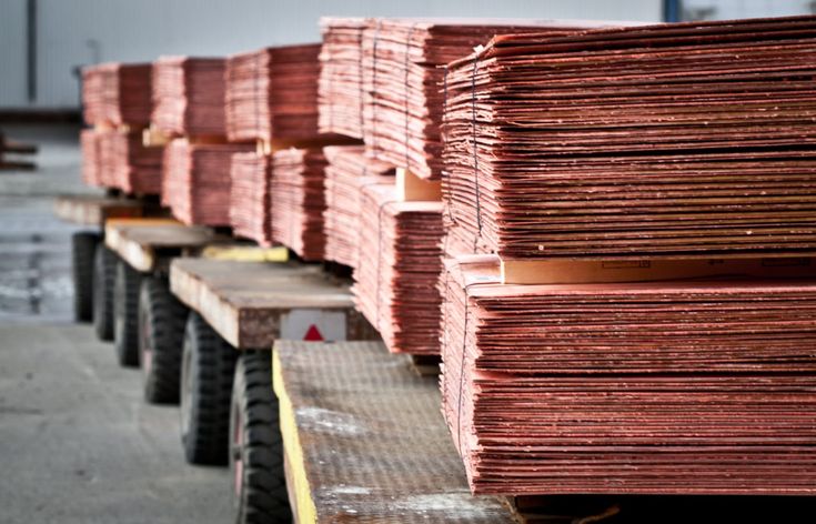 stacks of red wood sitting on top of each other in front of a warehouse building