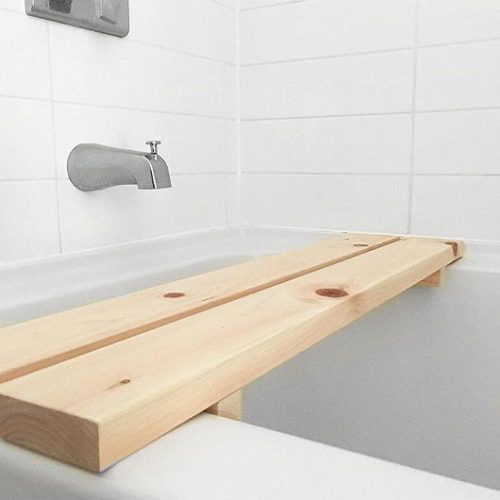 a wooden bench sitting in the middle of a bathtub next to a faucet