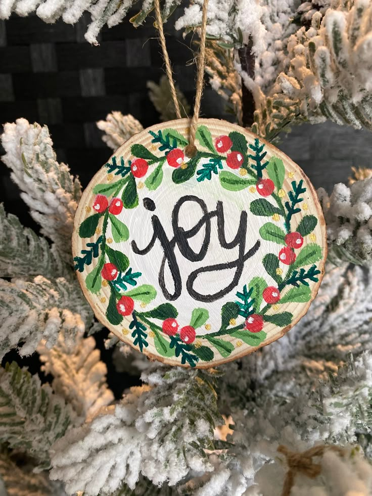 an ornament hanging from a christmas tree with the word joy painted on it