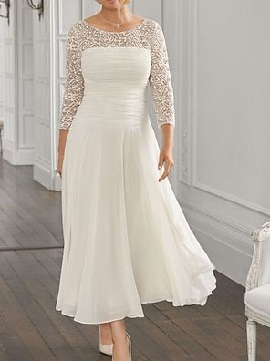 a woman in a white dress standing on a wooden floor next to a chair and wall