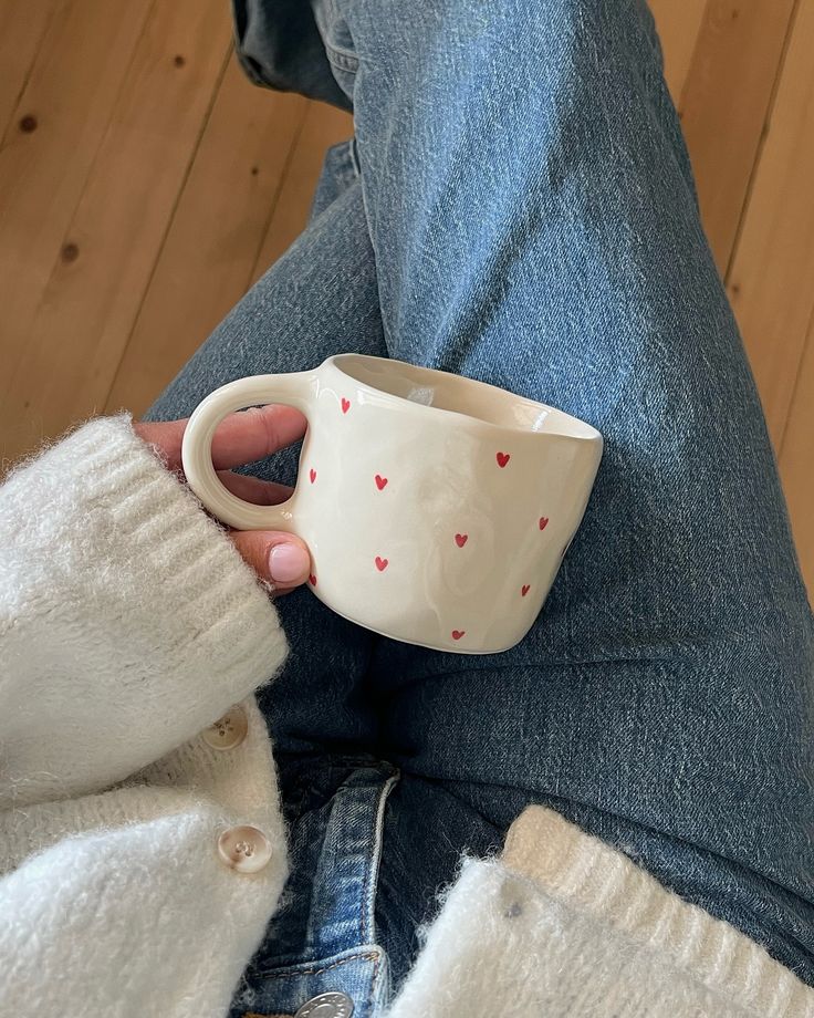 a person holding a coffee cup with hearts on it and their legs in the air