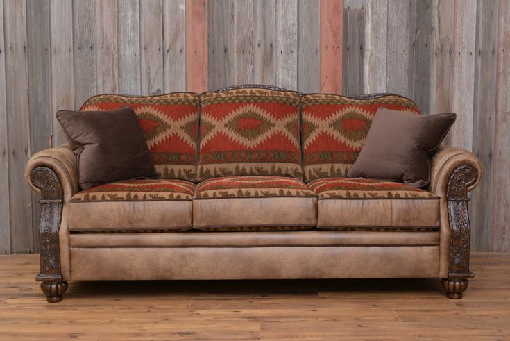 a couch with pillows on it in front of a wooden wall