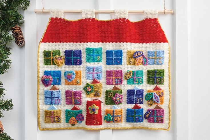 a crocheted house hanging on a wall with buttons and magnets attached to it