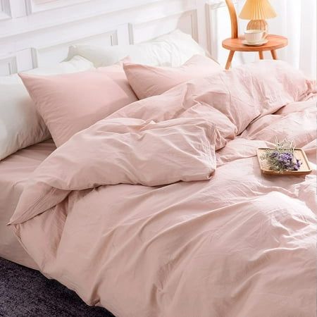 an unmade bed with pink sheets and pillows