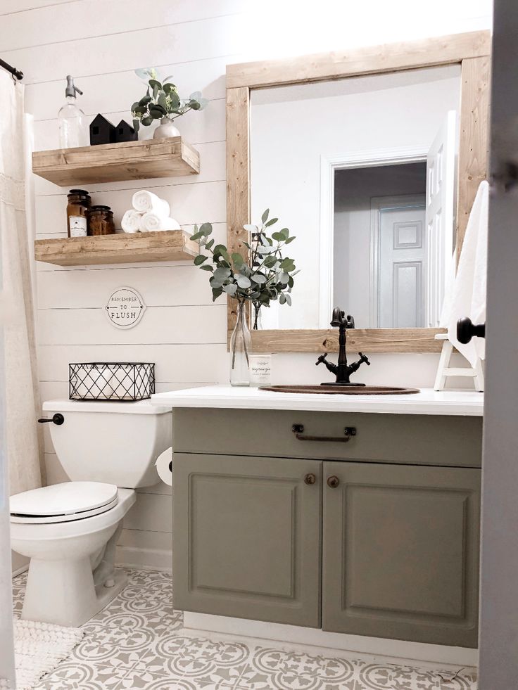 a white toilet sitting next to a bathroom sink under a wooden mirror mounted above it