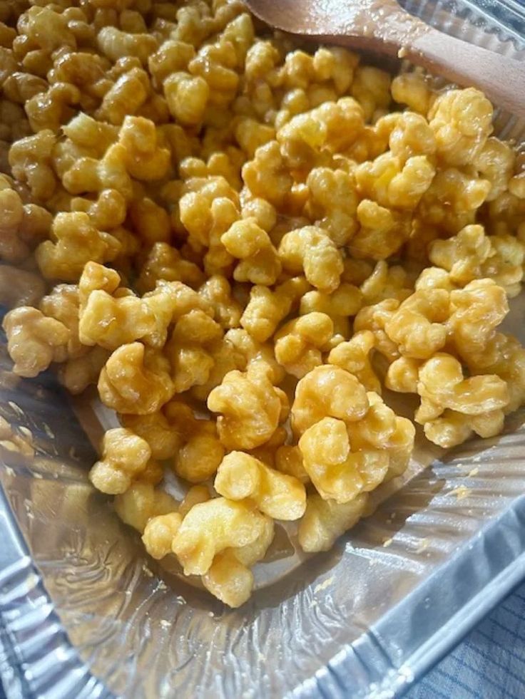 a glass bowl filled with corn kernels and a wooden spoon on top of it