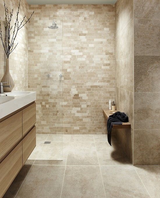 a modern bathroom with beige tile walls and flooring