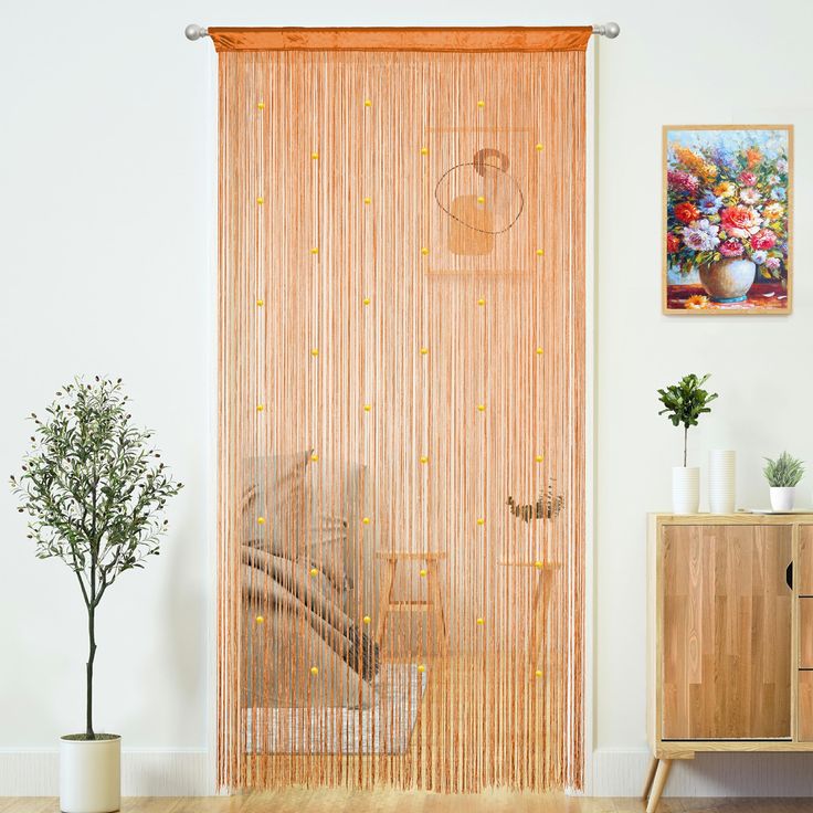 a living room with a wooden floor and sliding glass door that has gold beads on it