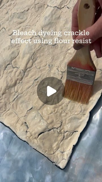 someone using a brush to paint the crackle effect on a piece of marbled paper