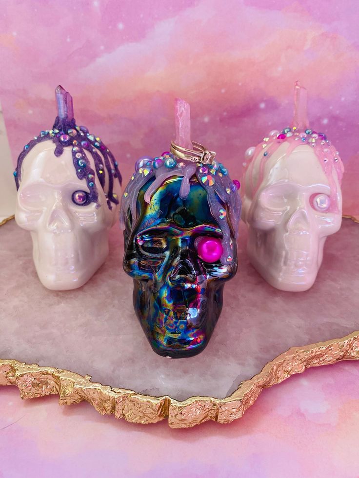 "This listing is for one skull ring holder of your choosing.  Photos have been linked and labeled for your convenience.  Choose your favorite color option!  Descriptions below.  Each skull is made from pearlized coated ceramic.  Genuine colored crystals are used for the ring holder, with cascading colored glue featuring embellishments.   Each skull is approximately 4\" tall by 3.5\" wide. Skull A: White pearl ceramic with pink glitter melt and aura pink quartz crystal. Skull B: White pearl ceram Pearl Ceramic, Pink Quartz Crystal, Aura Pink, Aura Blue, Witchcraft Supplies, Gothic Gifts, Purple Quartz, Mushroom Decor, Hanging Crystals