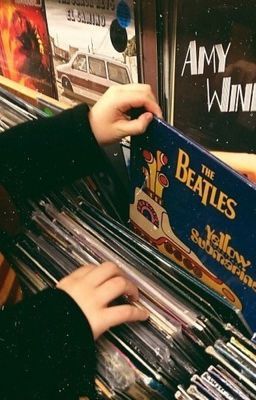 a person holding up a record player in front of a rack of vinyl records at a store