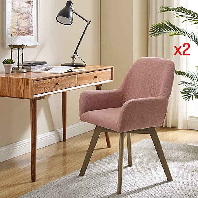 a pink chair sitting in front of a desk with a lamp on top of it