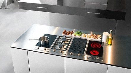 a stove top oven sitting inside of a kitchen next to a counter with cooking utensils on it