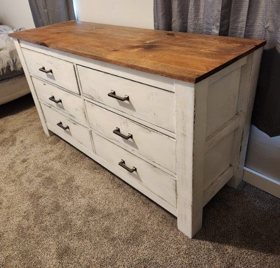 an old dresser is painted white and has wood top on it's drawers,