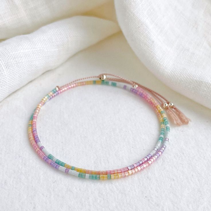 Our Shimmer Rainbow bracelet is made to catch the light when you move with rainbow coloured glass beads and silver sliding clasp to adjust length.  The silk cord is a pale pink colour and the beads are high quality glass beads in pink, peach, yellow, green, pale blue and lilac. Fits an average wrist size of up to 7 inches and tightens to 6.25in. Extends to maximum of 8.5in to fit over the widest part of the hand. If you have a small wrist and hands and would like a smaller bracelet size please contact me. Displayed in one of our pretty gift boxes, so fantastic as a present for a friend or to yourself! Check out the matching necklace https://www.etsy.com/uk/listing/1279385760/beaded-shimmer-rainbow-necklace-dainty Shipping Uk: 2-3 days - Royal Mail 48hr tracked International standard delive Colorful Adjustable Round Bead Bracelets, Colorful Adjustable Bracelets With Round Beads, Rainbow Sliding Knot Bracelets For Friendship, Rainbow Sliding Knot Bracelet For Friendship, Adjustable Colorful Hand-strung Bracelets, Colorful Adjustable Hand-strung Beaded Bracelets, Rainbow Sliding Knot Friendship Bracelet, Adjustable Rainbow Friendship Bracelets With Colorful Beads, Adjustable Rainbow Friendship Bracelet With Colorful Beads