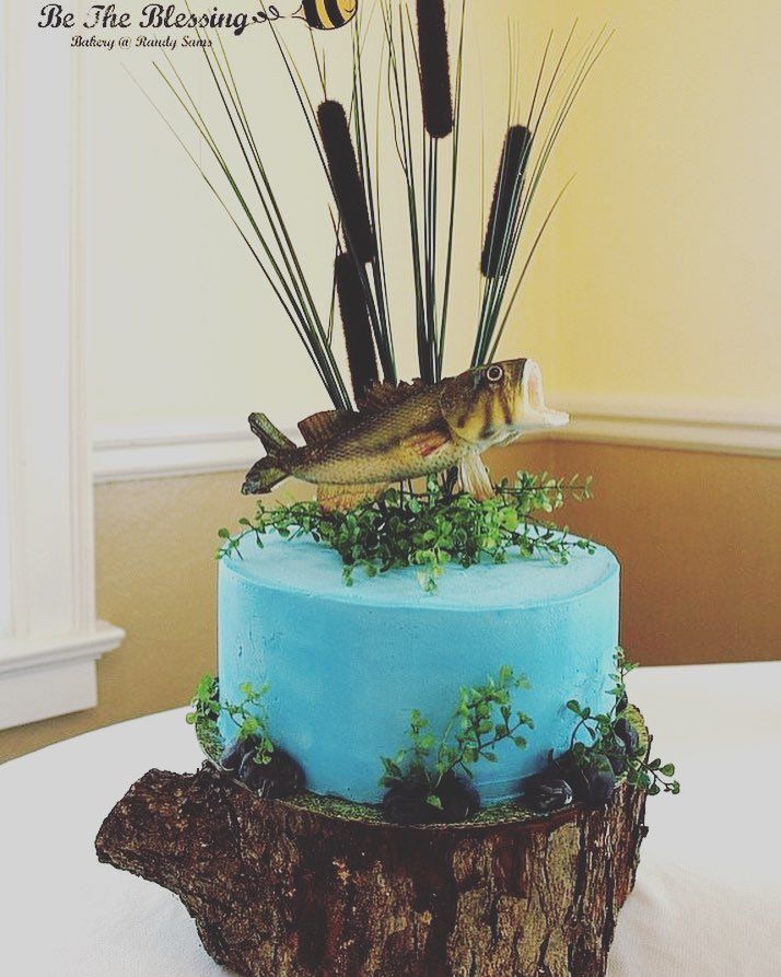 there is a blue cake with fish and plants on the top, along with fishing rods sticking out of it