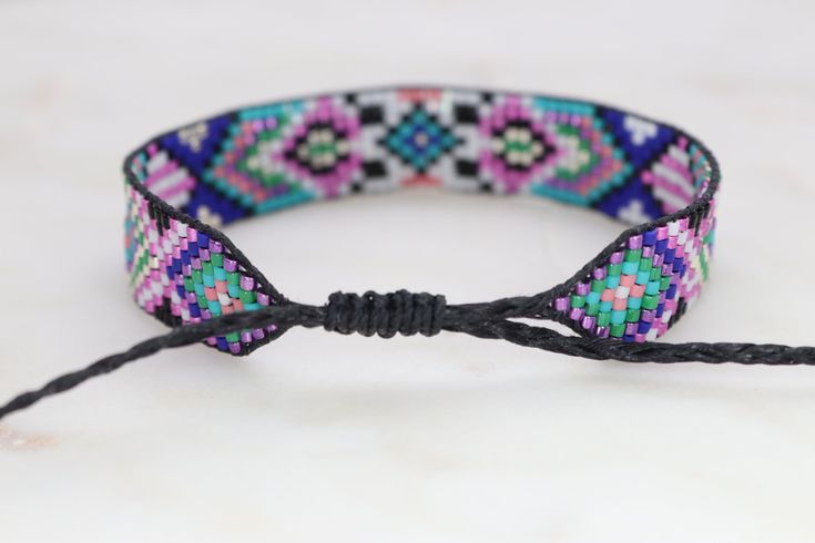 Introducing our adjustable southwestern beaded cuff bracelets! This colorful cuff bracelet is handmade with a southwestern-inspired pattern in shades of black, white, turquoise, coral, green, cobalt blue, and metallic pink. The bracelet is strung on strong beading thread and flexible beading cord with an adjustable closure, making it easy to put on and take off, while also allowing you to customize your fit. Whether you're dressing up for a special occasion or just accenting your everyday style, Painted Desert, Bead Loom Pattern, Beading Cord, Beading Thread, Beaded Cuff Bracelet, Bead Loom Bracelets, Bead Loom, Loom Bracelets, Southwestern Jewelry