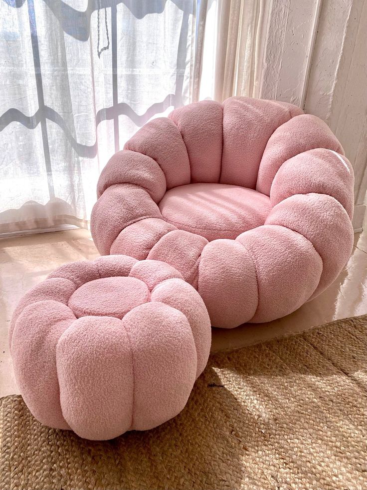 a pink chair and ottoman sitting on top of a rug in front of a window