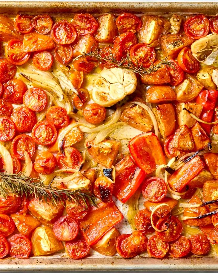 roasted tomatoes and onions in a baking pan with rosemary sprigs on the side