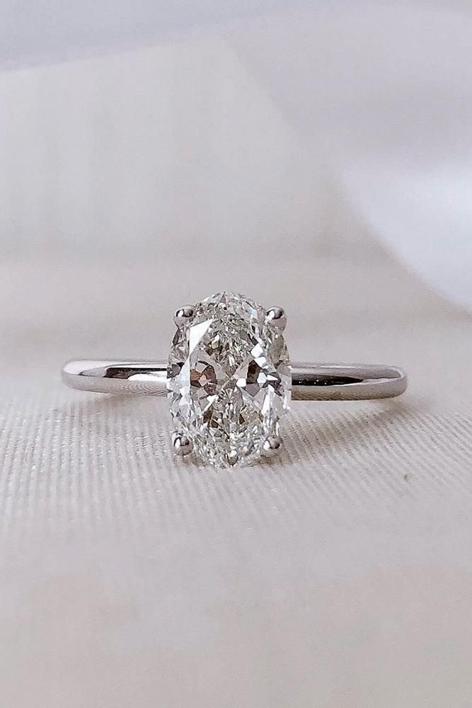 an oval cut diamond ring on a white surface