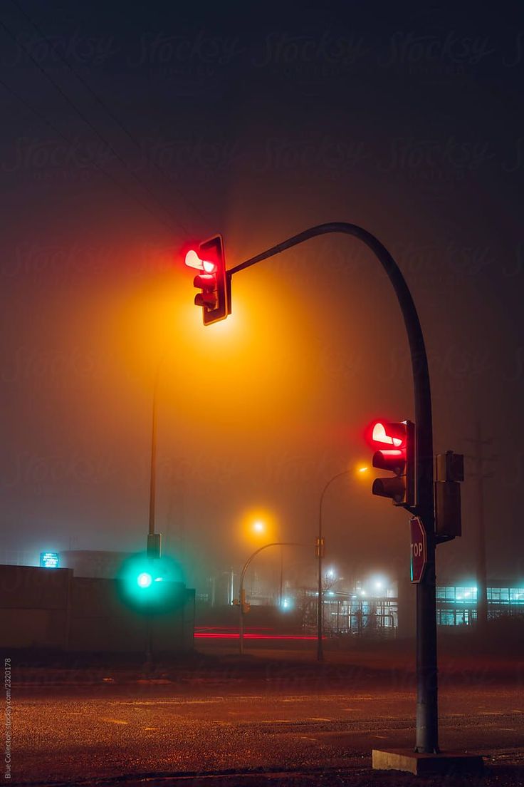 two traffic lights on a foggy street at night