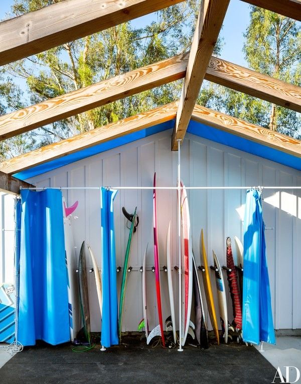 surfboards are lined up against the wall in front of an open garage door,