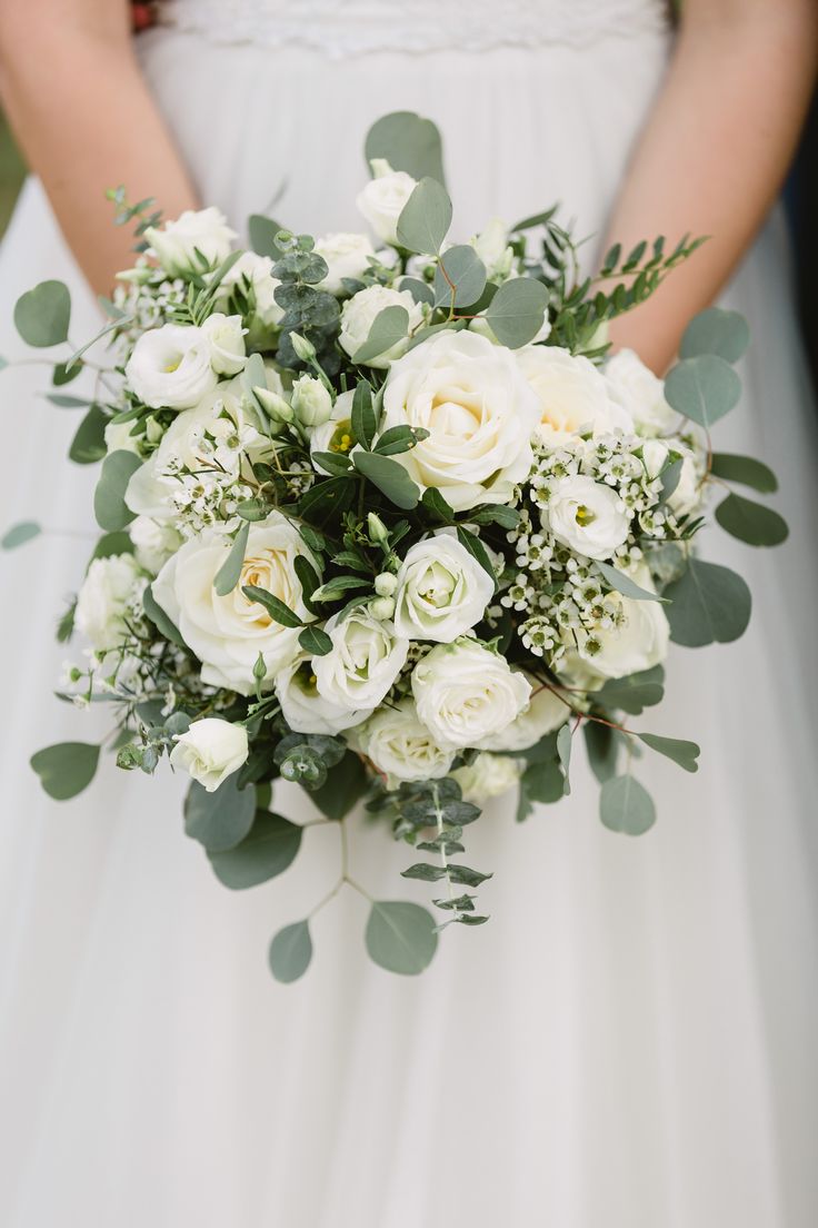 a bridal holding a bouquet of white flowers and greenery