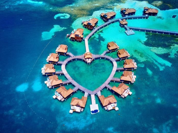 an aerial view of a heart - shaped island in the middle of the ocean with overwater huts