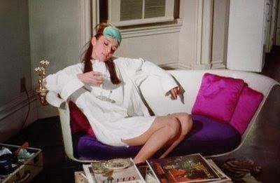 a woman sitting on a couch surrounded by magazines