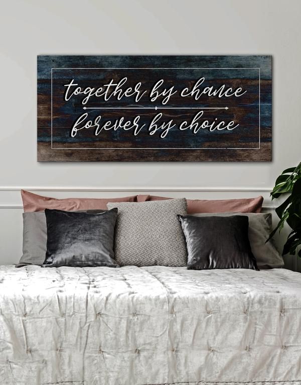 a wooden sign that says together by chance, forever by choice on the wall above a bed