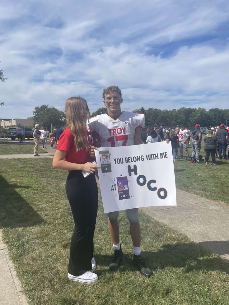 a man and woman standing next to each other holding a sign