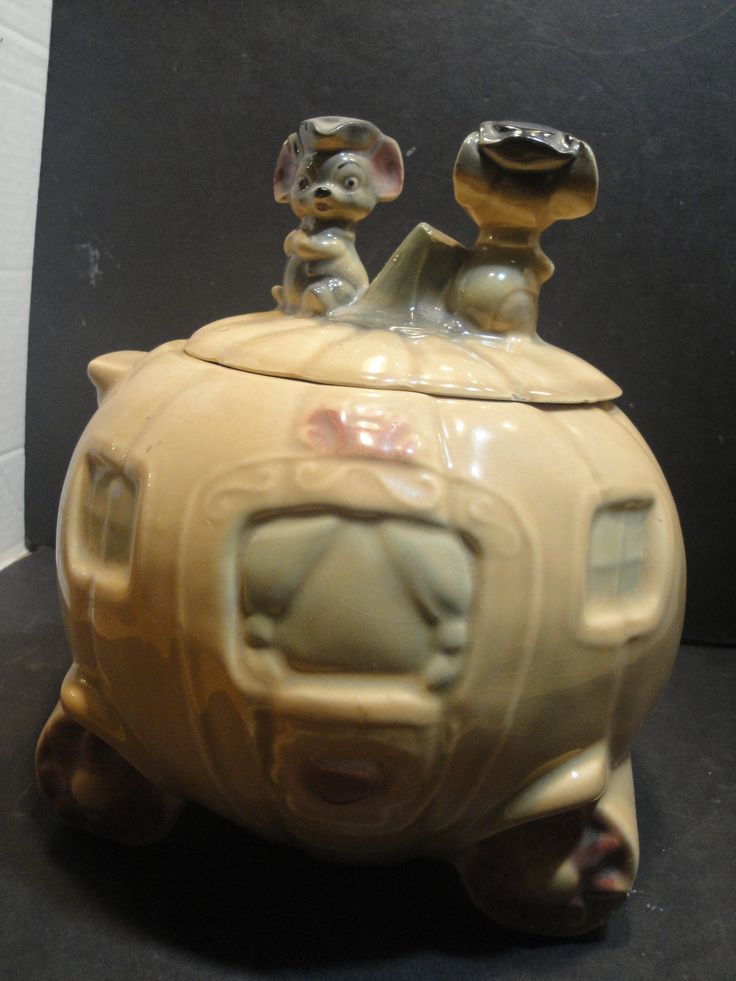 a ceramic container with two small dogs sitting on it's top and one is in the shape of a car