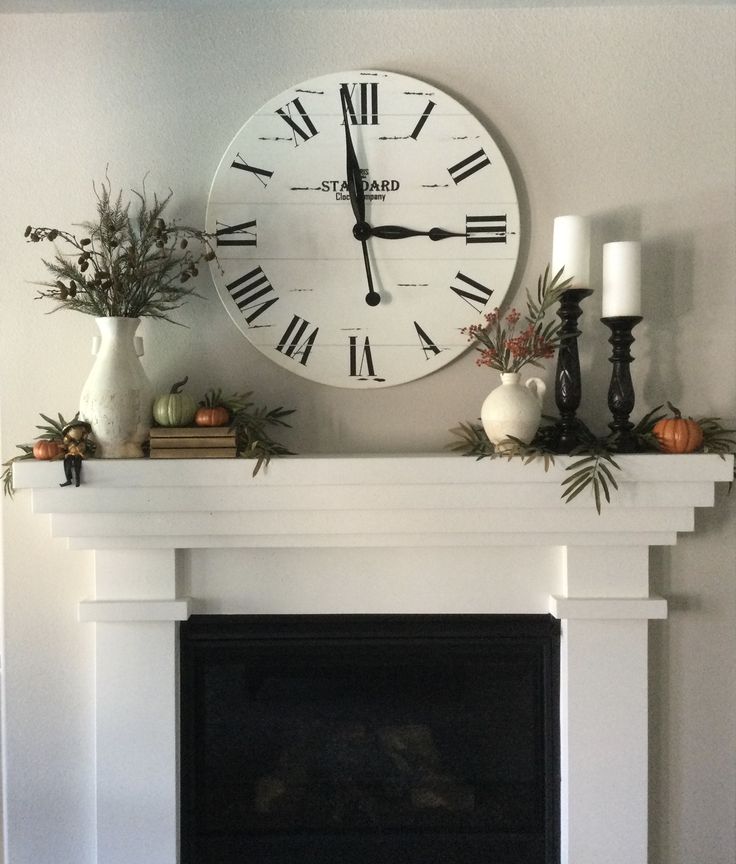 a fireplace with a clock above it and candles on the mantels next to it