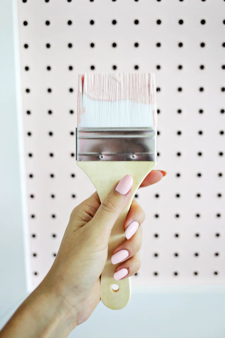 a woman holding a paint brush in front of a wall with polka dotes on it