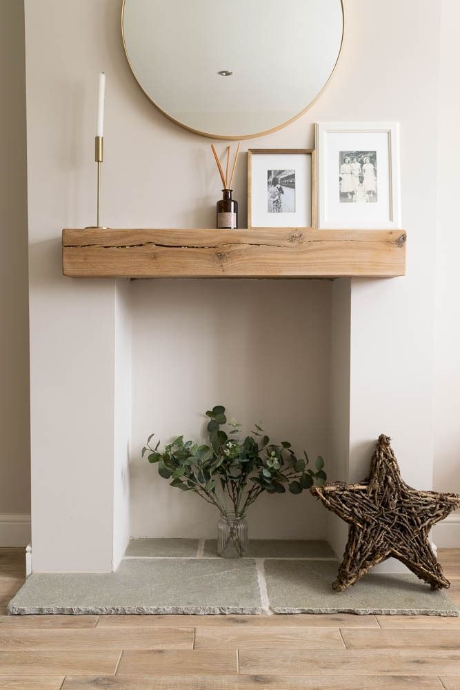 a white fireplace with a mirror above it and some plants on the mantle next to it