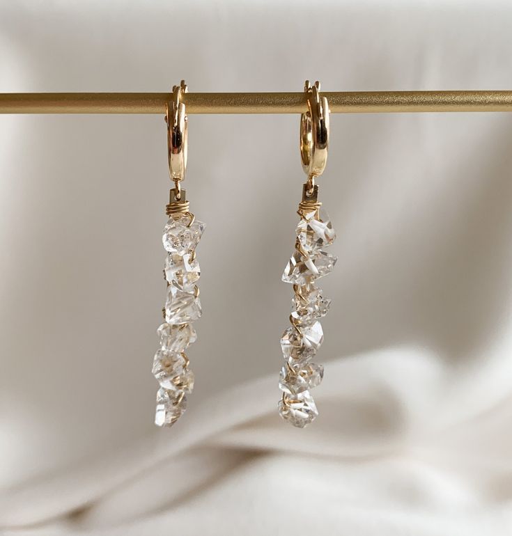 Herkimer crystals measure approximately 7mm drop length: 40mm/1.5″ hoop diameter: 13mm A striking and edgy crystal encrusted statement earring featuring six gorgeous Herkimer diamond quartz crystals.  The crystals are wire wrapped to 14k gold filled bars and suspended from Euro style hoop earrings that latch securely.   All hardware is 14k gold filled.  Herkimer crystals are double pointed resulting in maximum sparkle and shine.   Herkimer "diamonds" are double-pointed quartz crystals affectiona Crystal Earrings With Sparkling Stones For Anniversary, Crystal Cluster Drop Earrings With Sparkling Stones, Sparkling Crystal Dangle Diamond Earrings, Faceted Teardrop Crystal Earrings For Parties, White Crystal Long Drop Earrings, Dangle Crystal Earrings With Pearl Drop, Crystal Drop Earrings As A Gift, Pearl Drop Teardrop Crystal Earrings, Crystal Drop Earrings For Anniversary