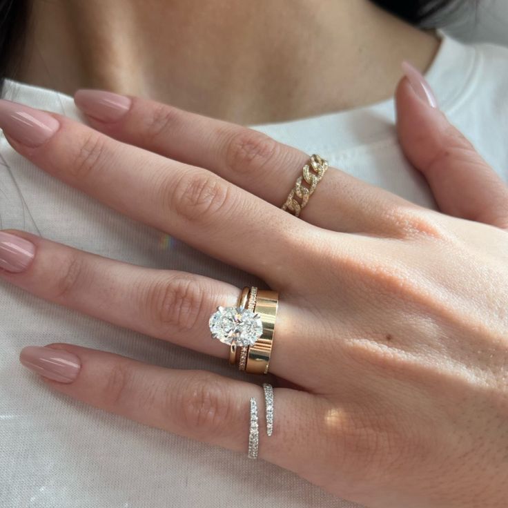 a woman's hand with three different rings on her fingers and one ring in the middle