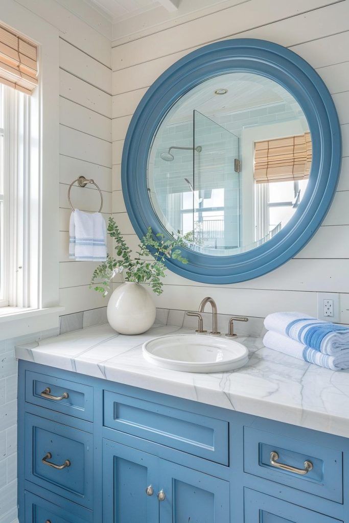 a bathroom with blue cabinets and a round mirror