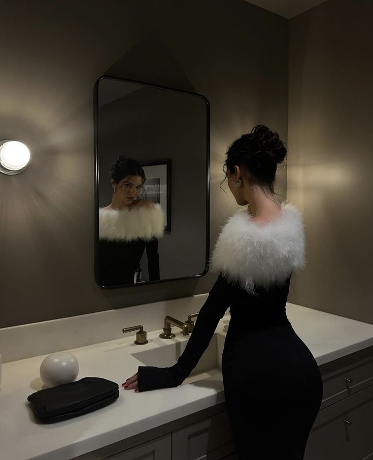 a woman standing in front of a bathroom mirror