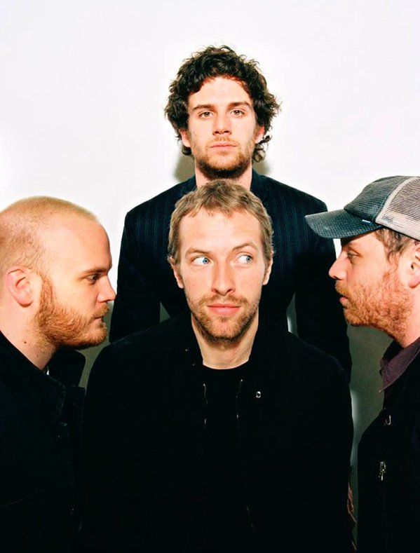 three men standing next to each other in front of a white wall with one looking at the camera