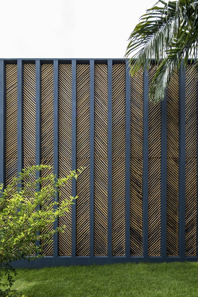 a wooden fence in the middle of a grassy area next to a tree and shrubbery