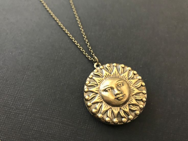 Bold Sun Hidden Locket Necklace... This celestial sun locket has an antique brass finish and is attached to an antique brass round locket. The chain is a non tarnish soldered antique brass rolo chain that closes with a lobster claw clasp. This is a unisex locket and would be a great gift for women and men! Locket - 1.25 inches in diameter (31.75mm) Interior photo area - 24mm Chain - 24 inches long This beautiful celestial locket will be mailed to you gift wrapped. A great gift to give your bride Bohemian Antique Gold Brass Locket Necklace, Antique Gold Medallion Locket Necklace In Bohemian Style, Bohemian Gold Brass Locket Necklace, Antique Gold Bohemian Medallion Locket Necklace, Bronze Bohemian Locket Necklace, Bohemian Antique Gold Medallion Locket Necklace, Bohemian Brass Medallion Locket Necklace, Vintage Locket Jewelry For Festivals, Vintage Festival Locket Jewelry