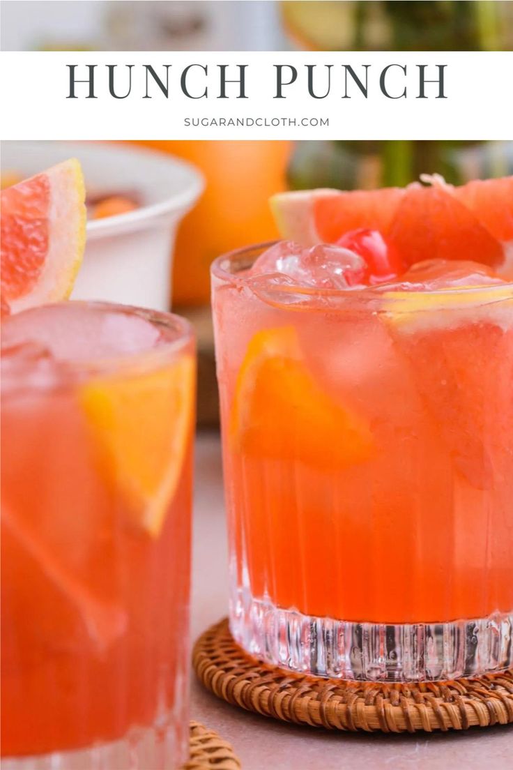 two glasses filled with watermelon punch and garnished with orange slices