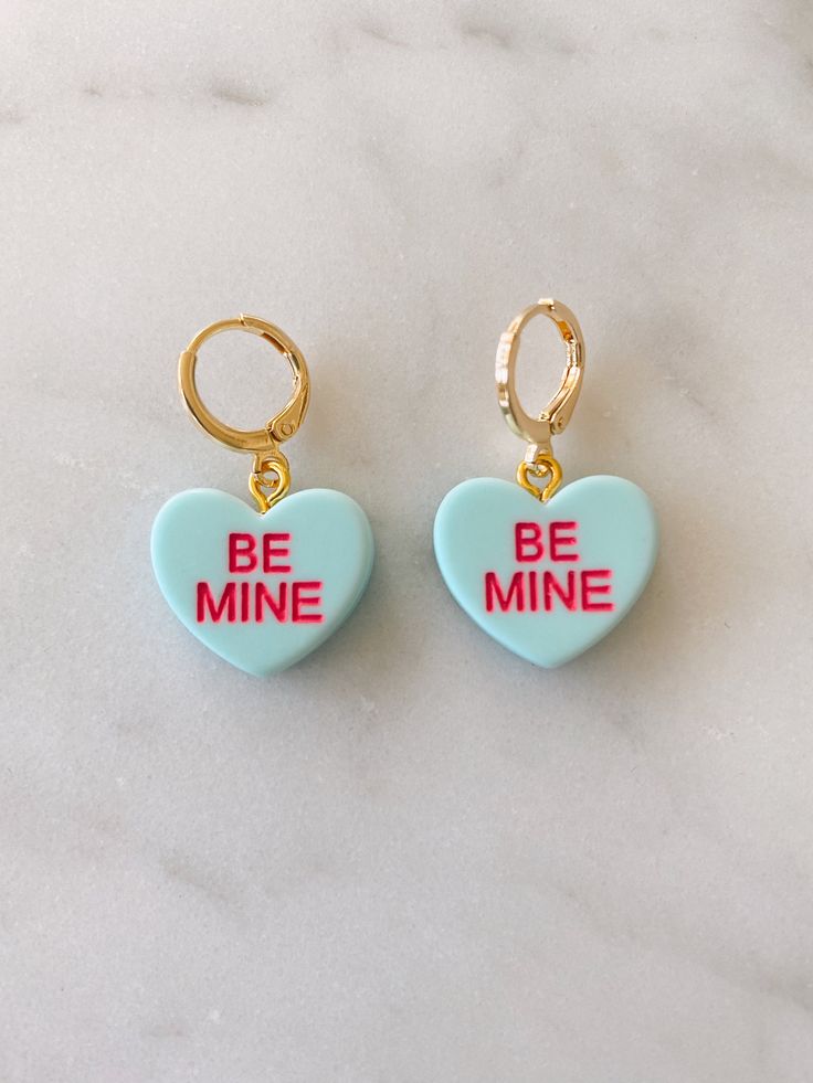 Obsessed is an understatement! Pay homage to your favorite Valentine's Day candies with these adorable be mine huggies. Available in both pierced hoops or clip on styles (for those without their ears pierced) these earrings are super fun and eye catching. Choose from a matte candy heart in a number of different colors or a two color glitter heart. The perfect size they are noticeable without being overwhelming. The charms are lightweight and easy to wear. Hoops are gold plated and nickel free. M Cute Single Earring Jewelry For Valentine's Day, Cute Single Earring For Valentine's Day, Valentine's Day Heart Huggie Earrings With Matching Set, Trendy Huggie Heart Earrings For Valentine's Day, Single Earring For Valentine's Day, Valentine's Day Heart Huggie Earrings For Pierced Ears, Cute Everyday Earrings With Heart Charm, Cute Heart Charm Earrings For Anniversary, Cute Dangle Hoop Earrings For Valentine's Day