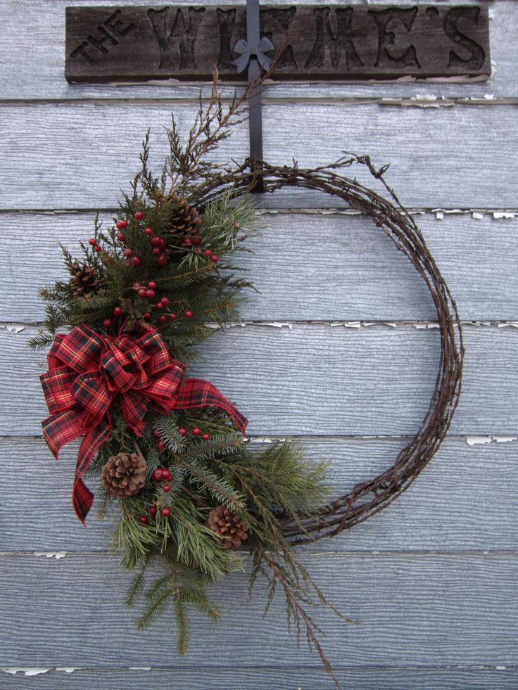 a wreath with pine cones and red berries hangs on the side of a building